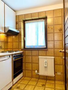 una cucina con pareti in legno, finestra e radiatore di Trilocale Golf Club a Madonna di Campiglio