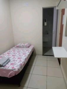 um pequeno quarto com uma cama e um chuveiro em Suítes em Belo Horizonte