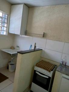 uma pequena cozinha com um fogão e um lavatório em Suítes em Belo Horizonte