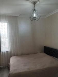 a bedroom with a bed with a chandelier and a window at Апартамент семейный in Batumi +2 photos