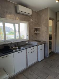 uma cozinha com armários brancos, um lavatório e uma janela em Nesea 2 em Psérimos
