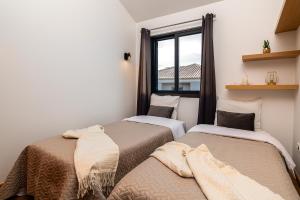 two beds in a room with a window at Melblue in Estreito da Calheta