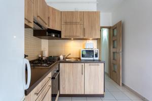 a kitchen with wooden cabinets and a microwave on the counter at Six Corners Bright Corner Comfortable City Apartment in Pécs +14 photos