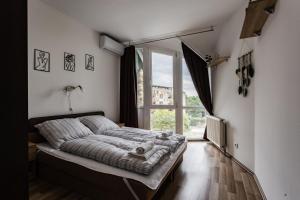 a bedroom with a bed and a large window at Six Corners Bright Corner Comfortable City Apartment in Pécs