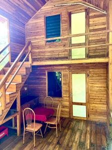 een houten hut met een tafel, stoelen en een trap bij Cat Ba Love House in Cat Ba