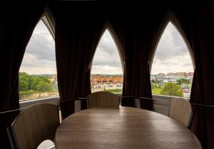a table with chairs in a room with windows at Six Corners Bright Corner Comfortable City Apartment in Pécs