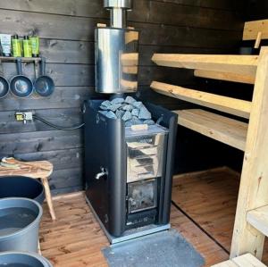 a stove in a room with a wooden wall at Pihasauna Mökki - Villa Alpaca Laamatila in Nokia