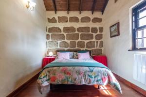 een slaapkamer met een bed in een kamer met een stenen muur bij Casa Rural Mi Perlita in Vega de San Mateo +16 foto's