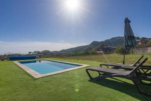 een stoel en een parasol naast een zwembad bij Casa Rural Mi Perlita in Vega de San Mateo