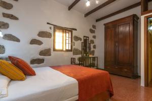 a bedroom with a bed and a wooden cabinet at El Zumacal in Valleseco