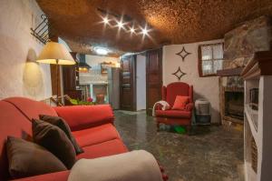 sala de estar con muebles de color rojo y chimenea en La Burbuja en Agua de Fontanales