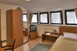 a bedroom with a bed and a desk and a tv at Hotel Am Markt in Kleinblittersdorf