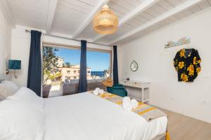 a bedroom with a white bed and a large window at Sa Dommu e Mare in Santa Maria Navarrese