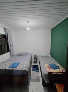 2 Betten in einem Zimmer mit grüner Wand in der Unterkunft Hostel Cápsula Pousada Avenida G20 in Canoinhas