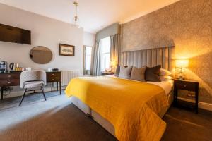 1 dormitorio con cama amarilla y escritorio en The Royal Wells Hotel, en Royal Tunbridge Wells