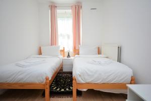 two twin beds in a room with a window at Lovely 3 Bedroom Apartment in Standford Hill in London