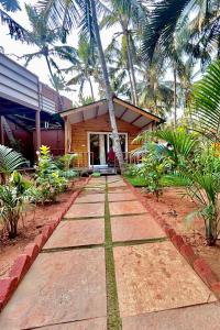 a walkway in front of a house with palm trees at Jardim a Mar in Agonda
