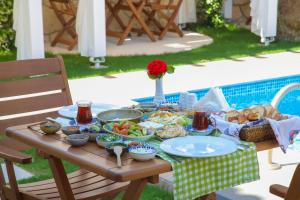 una mesa de picnic con comida junto a una piscina en Alacati Balbadem Hotel, en Alacati