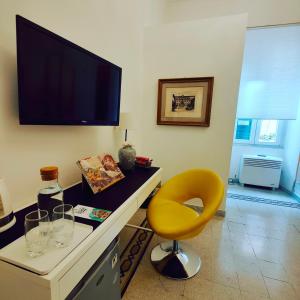 a living room with a yellow chair and a television on the wall at AcB Vaticano Suites in Rome