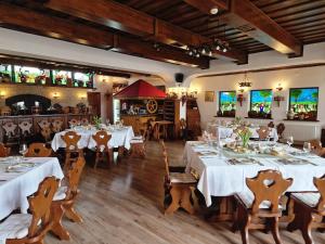 une salle à manger avec des tables blanches et des chaises en bois dans l'établissement Crama Haiducilor, à Cluj-Napoca