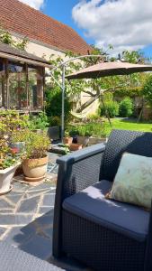 a patio with an umbrella and chairs and potted plants at Chambres d'hôtes bord de Loire in Saint-Mathurin