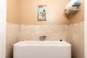 baño con bañera y una pintura en la pared en MASSiVE Bohemian Oasis in Philly 5 Bdrm Sleeps 12, en Filadelfia