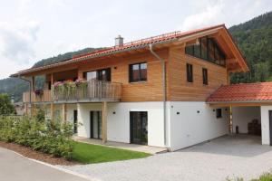 a wooden house with a balcony on a driveway at Villa Wanderlust in Reit im Winkl