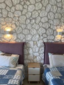 sypialnia z 2 łóżkami i kamienną ścianą w obiekcie Hamre Apartments (Nicholas) w mieście Agios Georgios Pagon