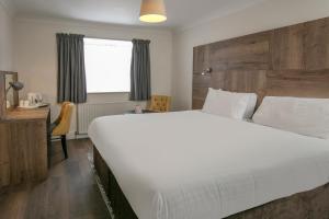 1 dormitorio con 1 cama blanca grande y escritorio en Best Western White House Hotel en Watford