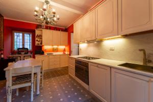 uma cozinha com armários brancos, uma mesa e um lavatório em Villa Lucia a Laglio by Wonderful Italy em Laglio