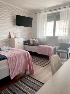 a bedroom with two beds and a flat screen tv at Szélrózsa apartmanház in Velence