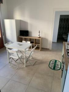 una cucina con tavolo e sedie bianchi in una stanza di Casa vacanze Marubium a Maruggio