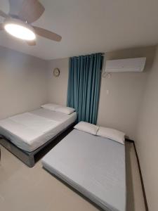 two beds in a small room with a ceiling fan at Condo Hotel near Mactan Cebu Airport in Mactan