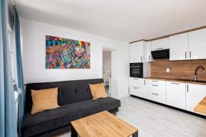 a living room with a black couch and a kitchen at Apartman Grey in Slunj