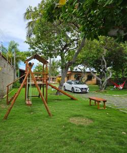 a park with a swing set and a bench and a car at Pousada Solar das Fontes in Beberibe