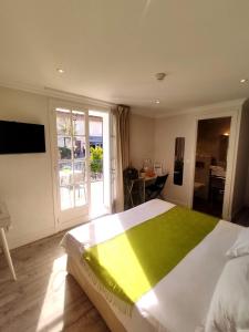 a bedroom with a large bed with a green blanket on it at Hôtel de la Corniche d'Or in Mandelieu-la-Napoule