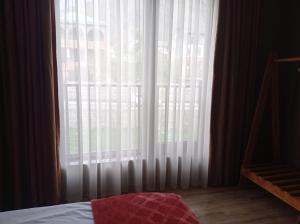 a bedroom with a large window with white curtains at Kazbegi 4U in Kazbegi