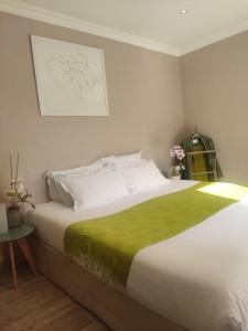 a bedroom with a large bed with a green blanket at Hôtel de la Corniche d'Or in Mandelieu-la-Napoule