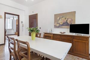 a dining room with a white table and a tv at Casa Grace - Casa al Mare in Vado Ligure