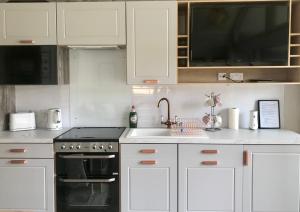 een keuken met witte kasten en een spoelbak bij Inverness Lodge-Sleeps 4-Mezzanine Level-Parking in Inverness +5 foto's