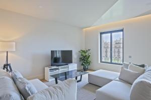 uma sala de estar com mobiliário branco e uma grande janela em Ola Living Paseo de Gracia em Barcelona