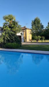 a blue swimming pool in front of a house at Chez Nanou, à proximité de St Emilion in Sainte-Terre