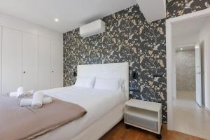 a bedroom with a white bed with a floral wallpaper at Housalia Casa del Mar en Vila Olímpica in Barcelona