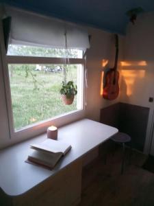 Habitación con una mesa con una ventana y una guitarra en Gezellige en frisse pipowagen bij Zutphen en IJssel, en Vierakker