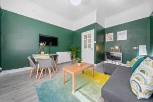 een woonkamer met groene muren en een tafel bij Townhead in Kirkintilloch