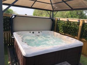 eine Whirlpool-Badewanne im Hinterhof mit Sonnenschirm in der Unterkunft Spacious Lodge With Hot Tub in Lincolnshire