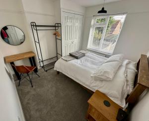 een slaapkamer met een bed, een spiegel en een raam bij Beautiful 4 Bedroom House Free Parking in Colchester