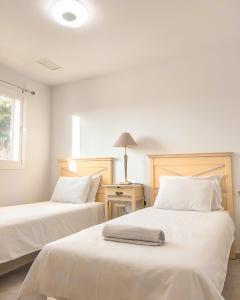 um quarto com 2 camas com lençóis brancos e um candeeiro em Albatross Golf Suite Alcaidesa em La Alcaidesa