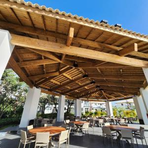 a patio with tables and chairs under a wooden pergola at Mykonos Praia do Forte in Praia do Forte