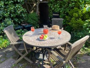 a table with a bowl of fruit and glasses of juice at Clay Farm Guest House in Bromley